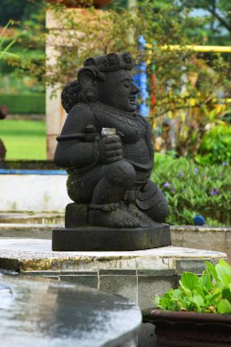Kuningan, Endonezya - Temmuz 06, 2025: Yeşillik yeşil bir park veya bulanık bir arka planda bulunan geleneksel bir Dwarapala koruyucu koruyucu heykeli.