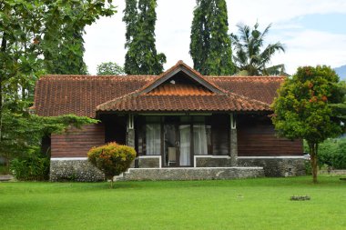 Endonezya, Batı Java 'da, Kuningan' da yemyeşil çimenler ve ağaçlarla çevrili, kırmızı kiremitli ve taş temeli olan güzel ahşap bir ev..