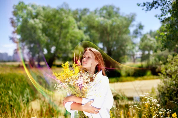 La fille tient un bouquet de fleurs sauvages à la main . — Photo