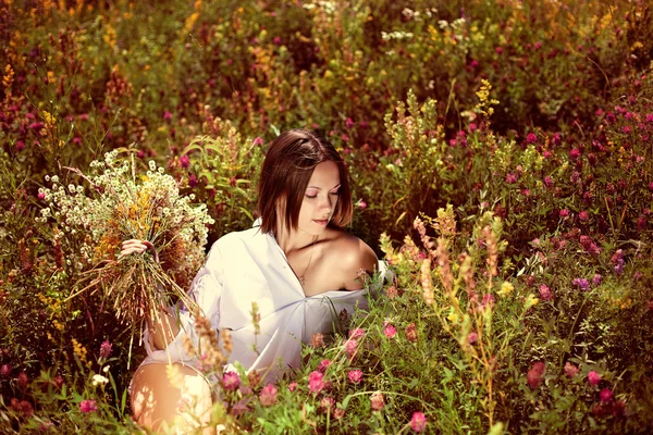 Het meisje houdt een boeket van wilde bloemen in de hand. — Stockfoto