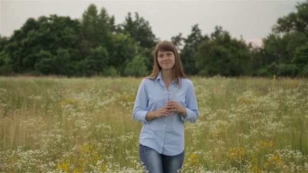 Het meisje in de weide met wilde bloemen — Stockvideo
