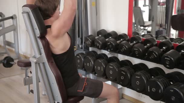 El hombre acumula músculos levantando una mancuerna en el gimnasio — Vídeo de stock