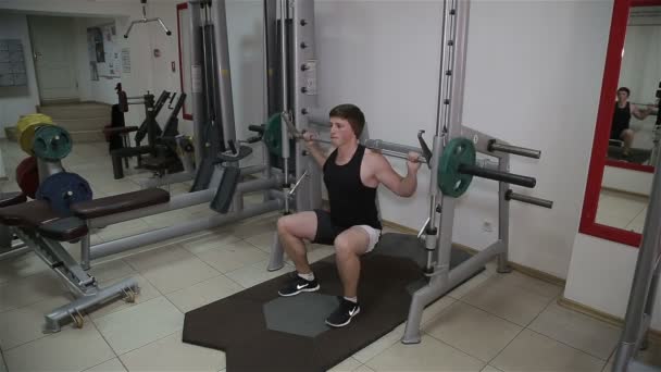 Mann hockt mit Langhantel im Fitnessstudio — Stockvideo