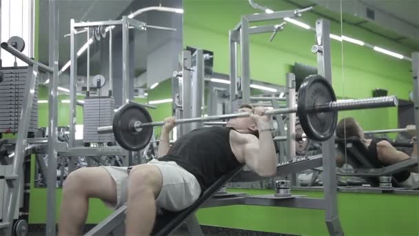 L'homme lève la barre dans la salle de gym — Video