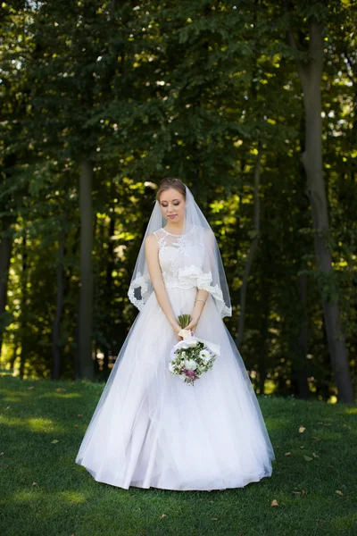Прекрасный свадебный букет в руках молодой невесты в белом свадебном платье . — стоковое фото