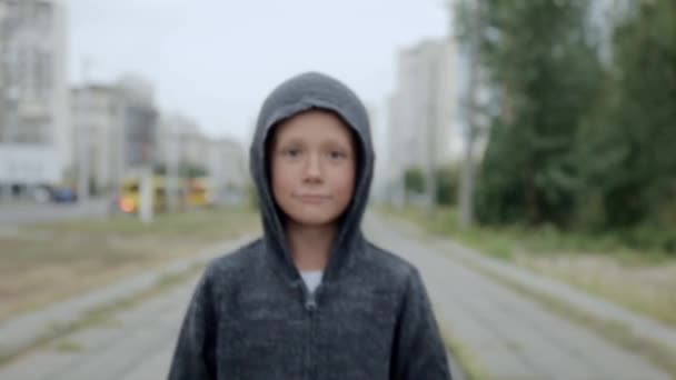 En pojke i svart huva på gatan — Stockvideo