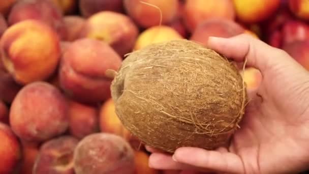 Kelapa di tangan wanita dengan latar belakang buah persik segar — Stok Video