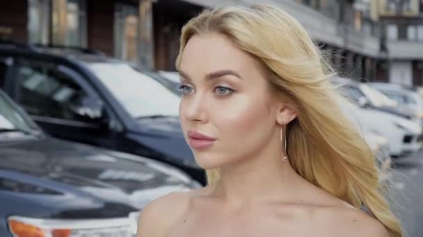 Portrait d'une blonde aux lèvres pleines et aux yeux bleus sur fond de parking — Video