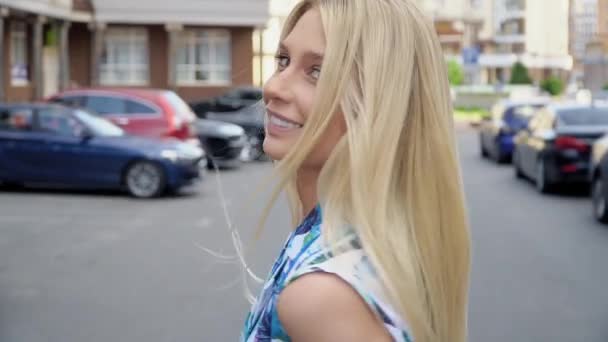 Rubia en un traje de verano posando en el estacionamiento. Cableado de cámara. Caminata de mujer — Vídeo de stock