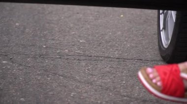 Yazlık ayakkabılı kadın ayakları arabadan sarkıyor.