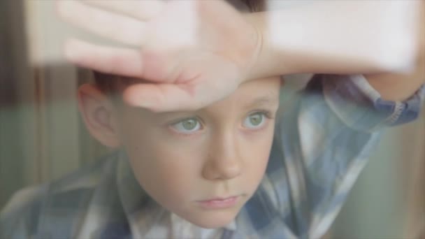 Ledsna barn ser ut genom fönstret — Stockvideo