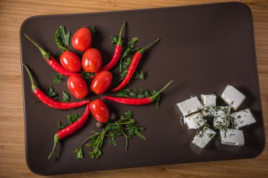 Domates ve biber ile peynir ve karanlık bir tabak üzerinde otlar