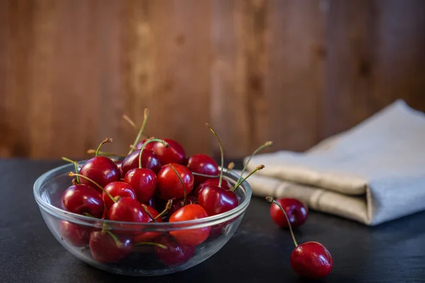 Cerises dans un bol en verre. Serviette. panneau de fond . — Photo