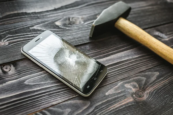 Smartphone mit kaputtem Display auf rustikalem Holzgrund — Stockfoto