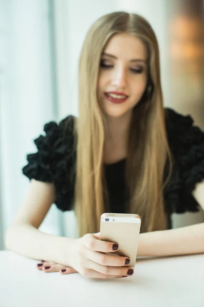 Mujer con teléfono en la mesa — Foto de Stock