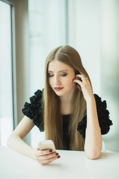 Mujer con teléfono en la mesa — Foto de Stock