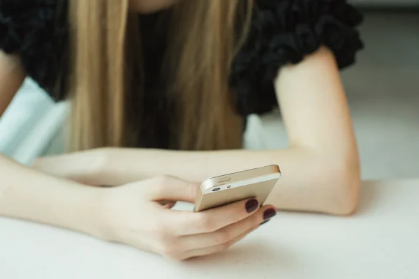 Mujer con teléfono en la mesa — Foto de Stock