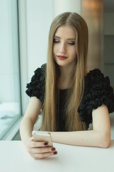 Mujer con teléfono en la mesa — Foto de Stock