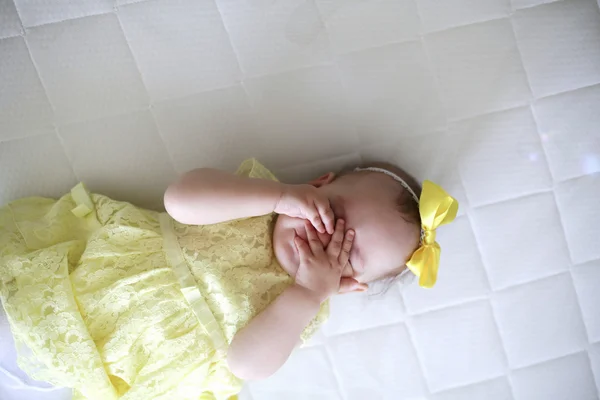 Menina em vestido amarelo na cama branca — Fotografia de Stock