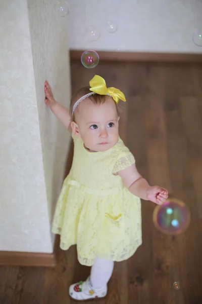 Bambina in abito giallo cattura bolle di sapone — Foto Stock