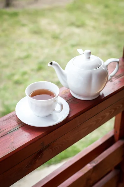 Cup of black tea and kettle on veranda — Stock Photo, Image