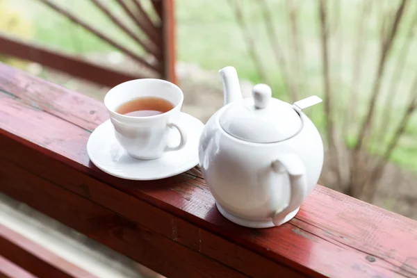Cup of black tea and kettle on veranda — Stock Photo, Image