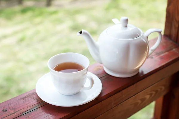 Cup of black tea and kettle on veranda — Stock Photo, Image