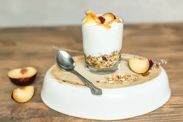 Sklo, müsli, cereálie, jogurt s broskví a švestek — Stock fotografie