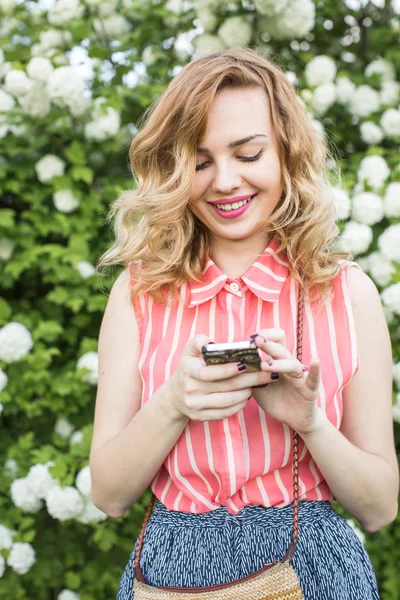 Portreit von attraktiven jungen Mädchen mit lockigem Haar hält Handy — Stockfoto