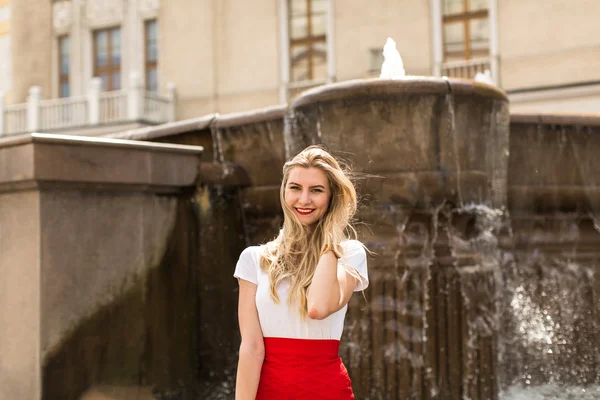 Счастливая молодая женщина с длинными волосами стоит у фонтана — стоковое фото
