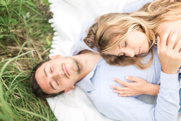 Young couple man and woman lie on the rug on nature, the concept — Stock Photo, Image