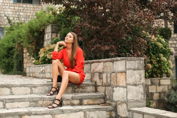 Ragazza in abito rosso in giardino sui gradini — Foto Stock