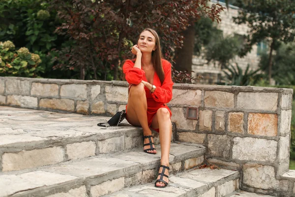 Ragazza in abito rosso in giardino sui gradini — Foto Stock