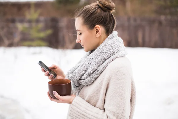 전화 및 겨울에 뜨거운 차를 젊은 여자 — 스톡 사진