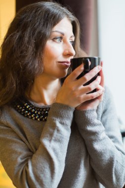 kız sıcak çay pencerede içecekler.