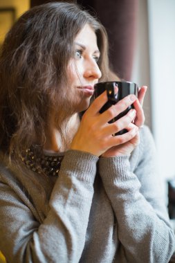 kız sıcak çay pencerede içecekler.