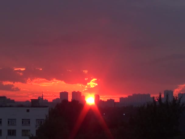 Яскравий захід сонця над горизонтом з сонячним диском за будівлями — стокове відео