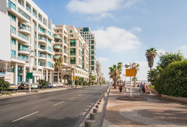 Motorväg längs banvallen med byggnader på vägkanten, parkering och människor gå längs. Tel Aviv, Israel. — Stockfoto