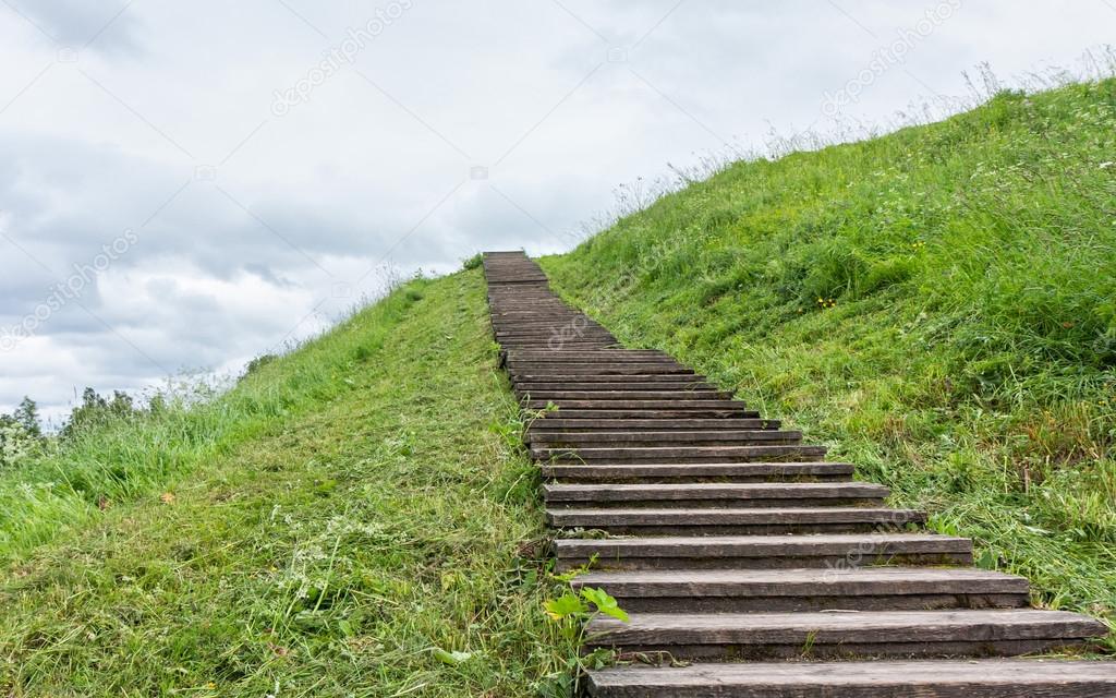 Long wood stairs to top of grass-covered earth-deposit