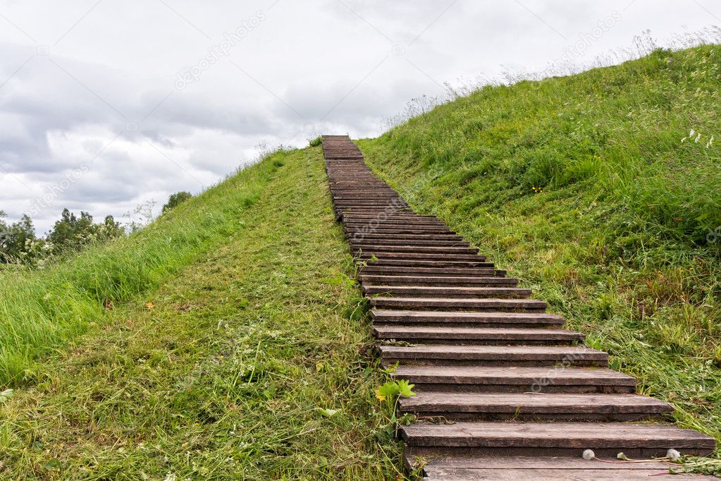 Long wood stairs to top of grass-covered earth-deposit