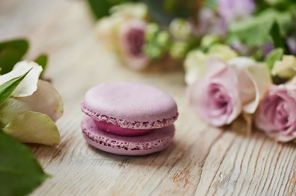 Pastel de macarrones púrpura con rosas en la mesa — Foto de Stock