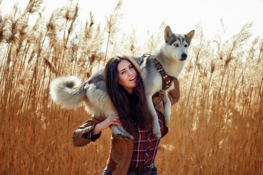genç kadın ile onun Sibirya husky köpek yavrusu bir alanda gün batımı sırasında oynamaya.