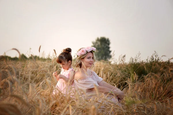 Matka i córka siedzi w polu żyta. — Zdjęcie stockowe