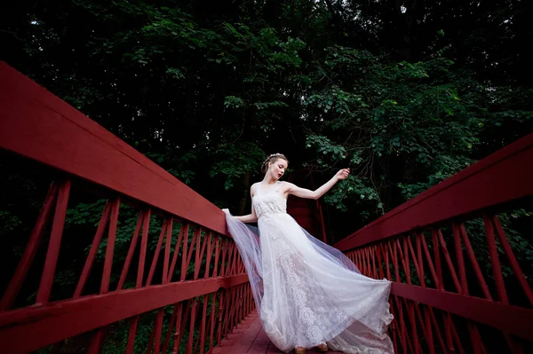 Genç güzel kız akan bir elbiseli kırmızı köprüde yürüyüş. — Stok fotoğraf