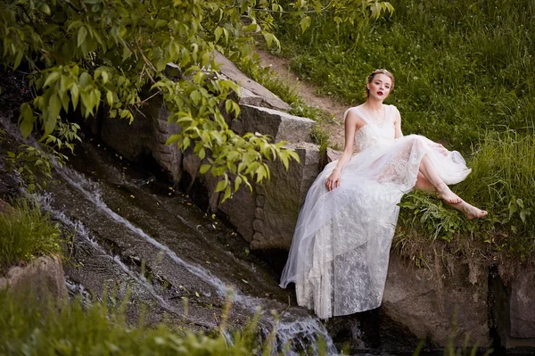 坐在瀑布穿白裙子的女孩。波西米亚风格 — 图库照片