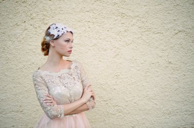 Güzel sarışın bir saç modeli ve peçe ile sağlam kum duvar, nötr renkler, pastel romantik görünüyor arka planı mı