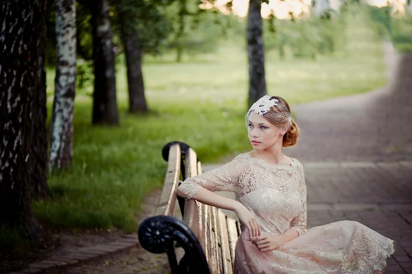 Bella bionda con acconciatura e velo seduta sulla panchina, look romantici — Foto Stock