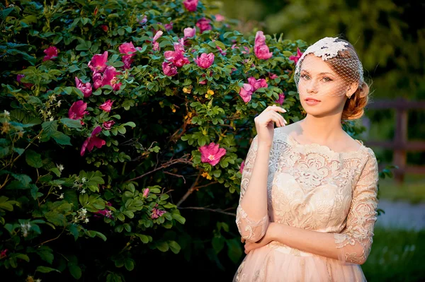 Vrij inschrijving blonde in een jurk lace crème tegen de achtergrond van een bloeiende tuin — Stockfoto