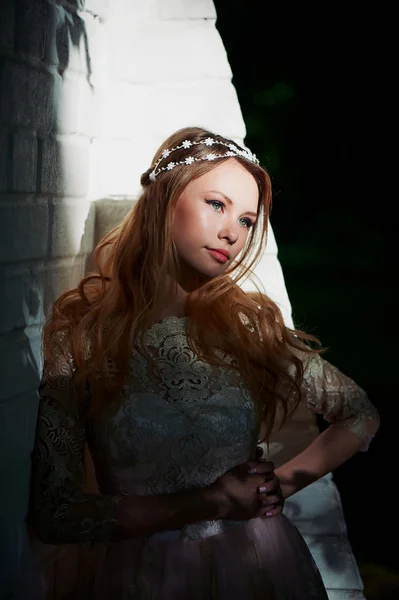 girl in bright lace dress stands in the shade of the trees, the light falls on the face. The spot