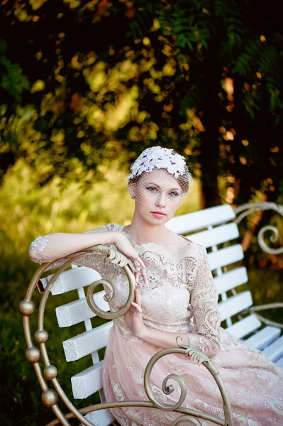 Belle blonde avec une coiffure et un voile assis sur un banc, look romantique — Photo